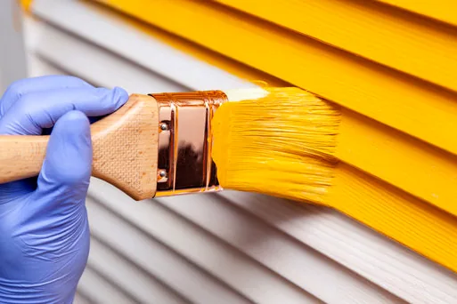 Brushing bright paint onto louvered shutters on a Magnolia Park home